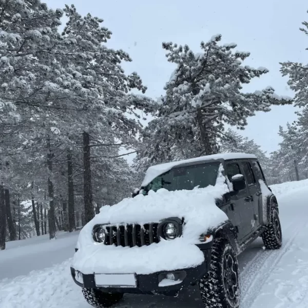 A snow-covered Jeep descends the mountain.